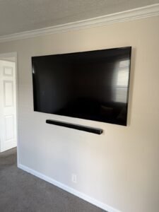 Wall-mounted TV with soundbar below on a painted wall