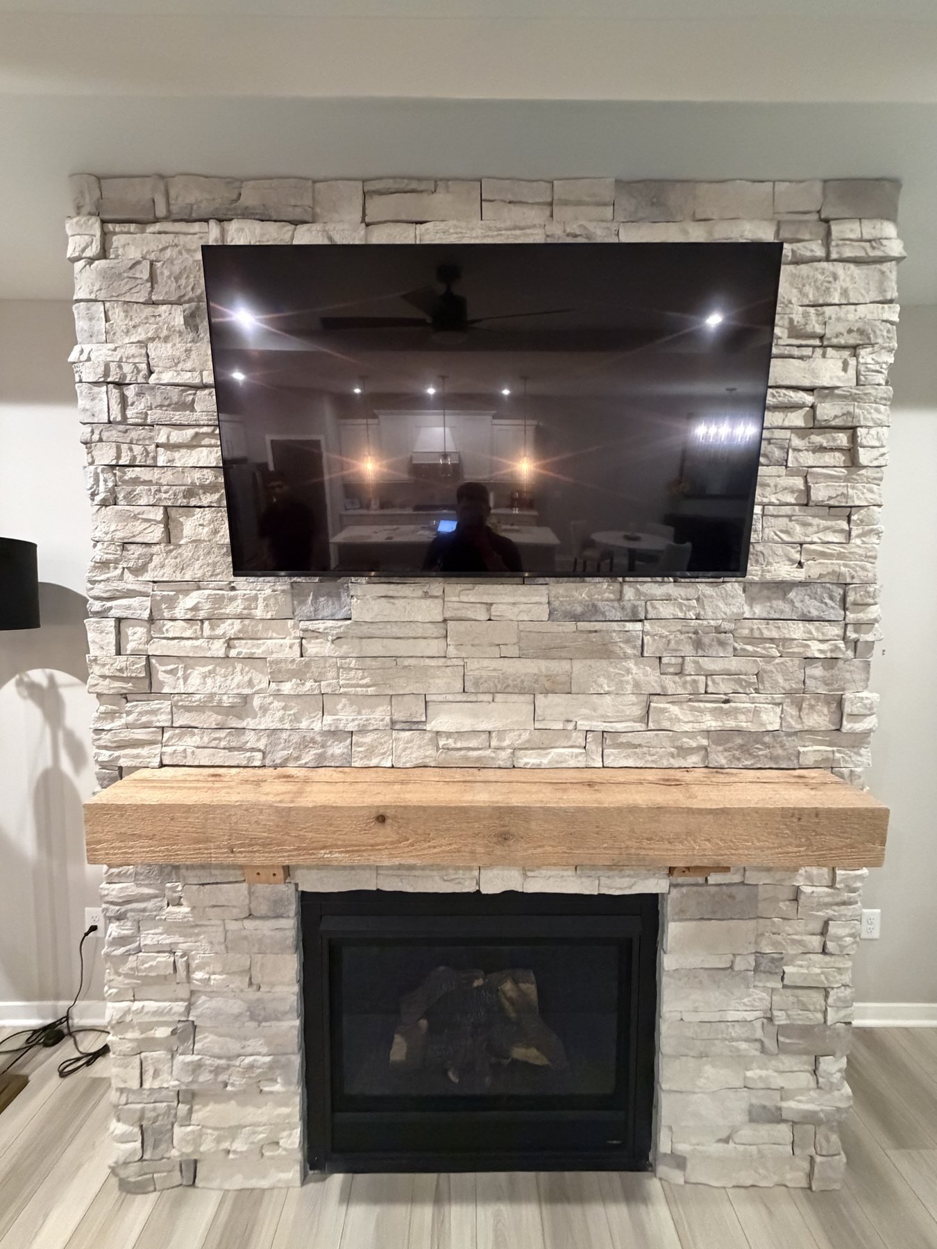 TV Mounting on Stone-Faced Fireplaces Angled view of TV, wood mantel and stone-faced fireplace wall